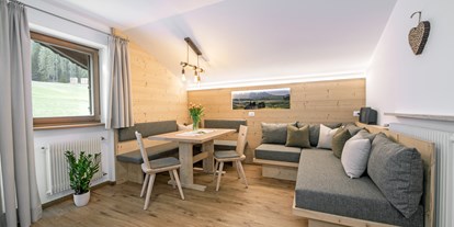 suche - Garten - Kastelruth - Wohnraum mit gemütlicher Sitzecke und Schlafcouch aus einheimischen Fichtenholz - Apartment Haus Pötzes