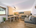 Unterkunft: Wohnraum mit gemütlicher Sitzecke und Schlafcouch aus einheimischen Fichtenholz - Apartment Haus Pötzes